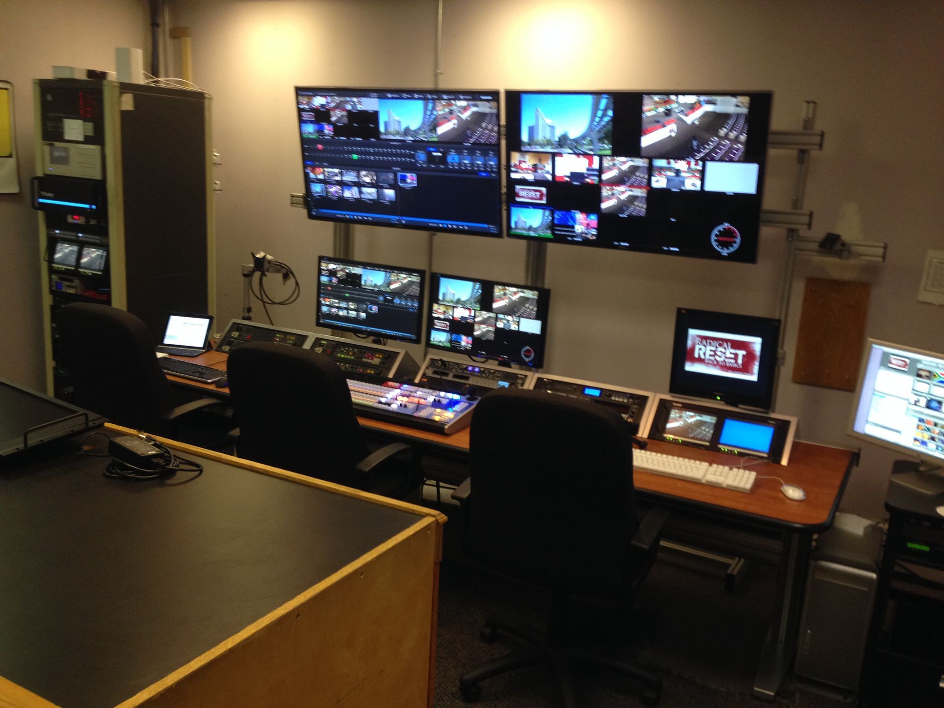 A television control room with multiple screens displaying video feeds and editing software.