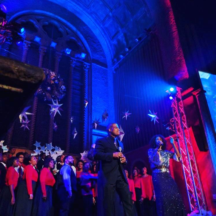 Choir performing on stage under blue and red lights.  Decorated with stars.