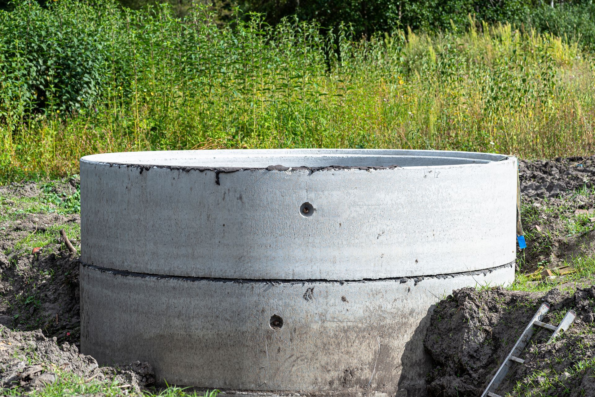 Concrete utility structure in a grassy field beside a dirt path