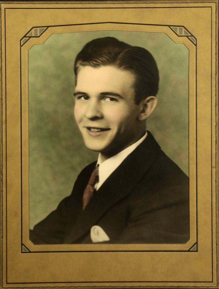 Framed vintage portrait of a smiling man in a dark suit and tie against a muted green background