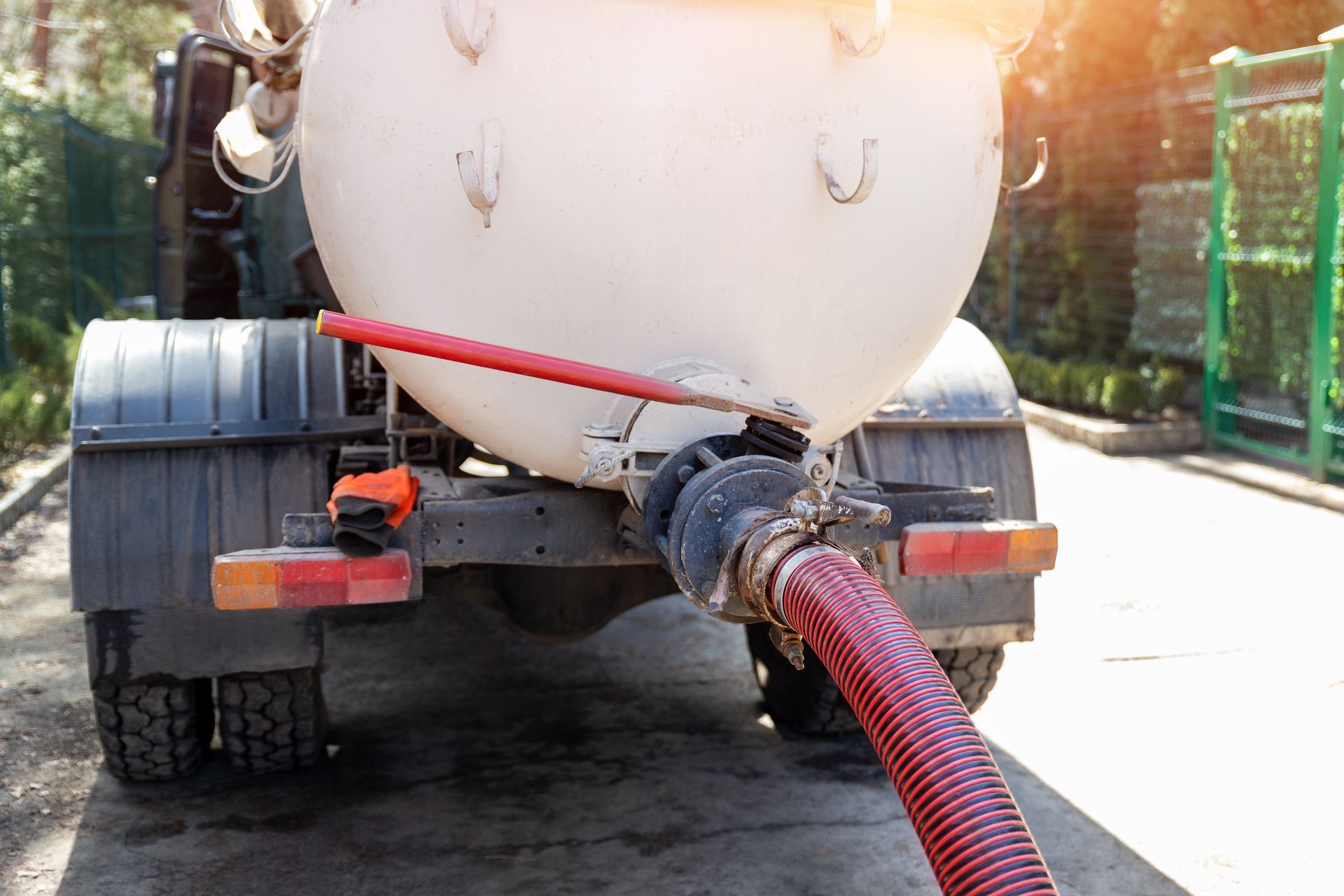 Vacuum tanker truck unloading wastewater through a large hose during professional septic service. Vacuum tanker truck unloading wastewater through a large hose during professional septic service.