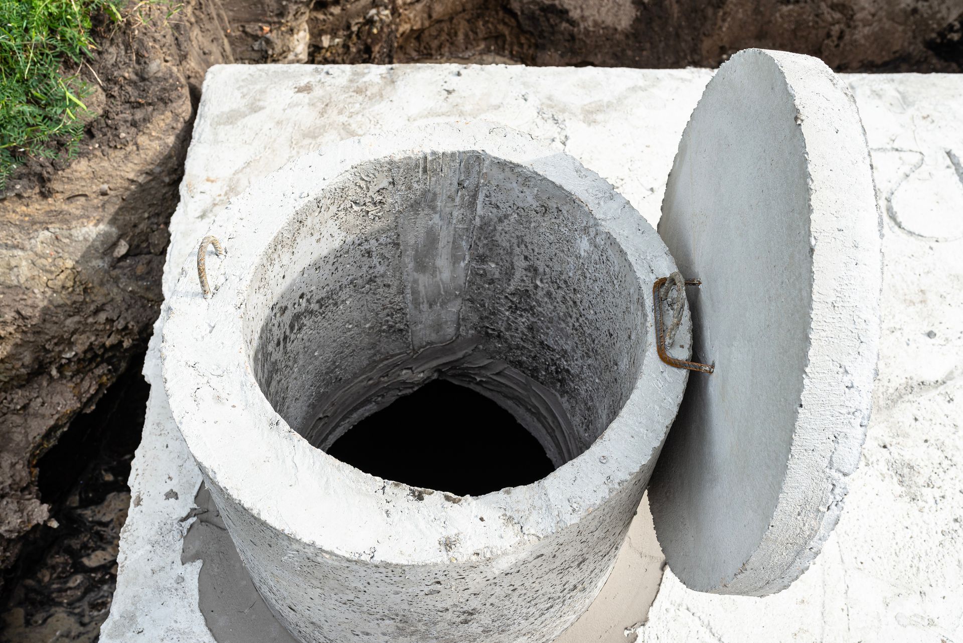A concrete septic tank with a capacity of 10 cubic meters is placed in the garden by the house, with visible water below