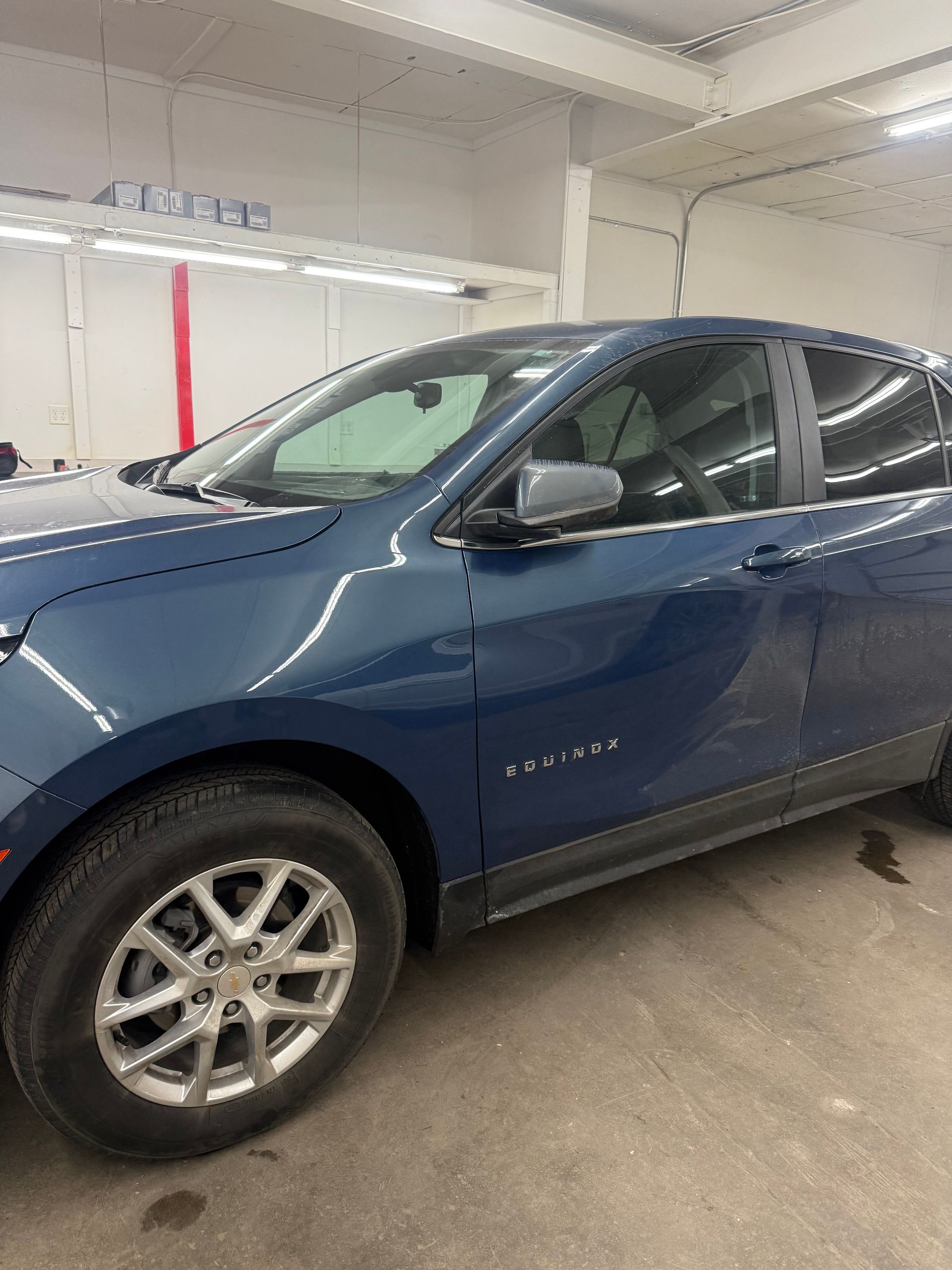 A blue Chevrolet Equinox SUV parked inside an indoor garage with overhead lighting.
