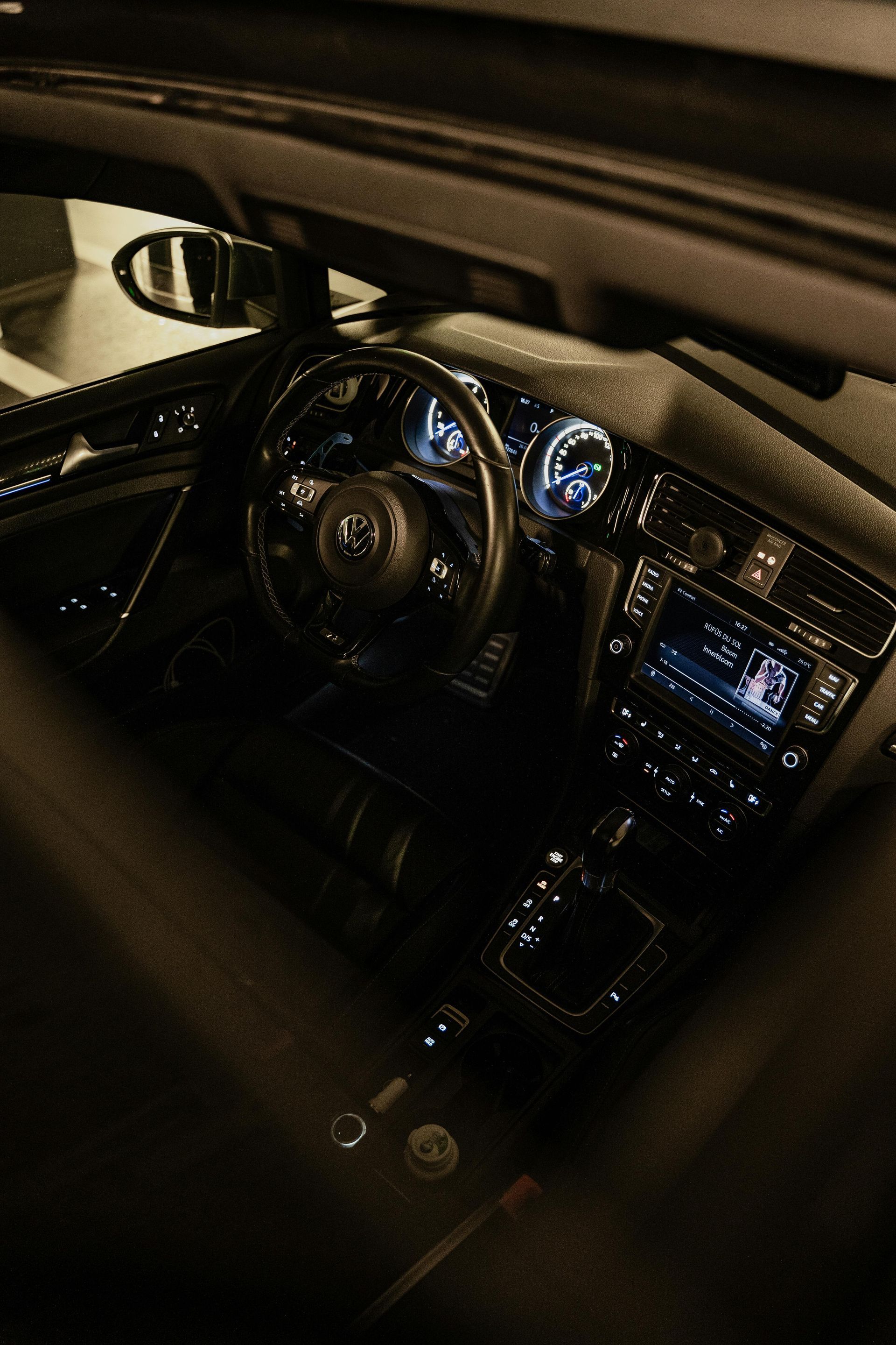 Interior of a dark car showing the steering wheel, digital dashboard, and center console touchscreen.
