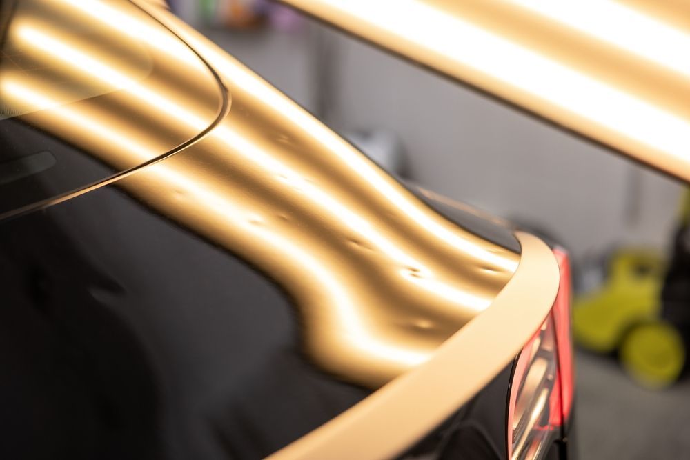 A close-up view of a car body panel with visible dents, illuminated by a light board to highlight imperfections.