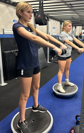 Two women exercising on balance discs in a gym