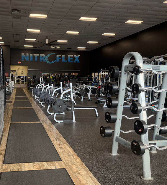 NitroFlex gym interior with rows of exercise machines and weight equipment under bright ceiling lights