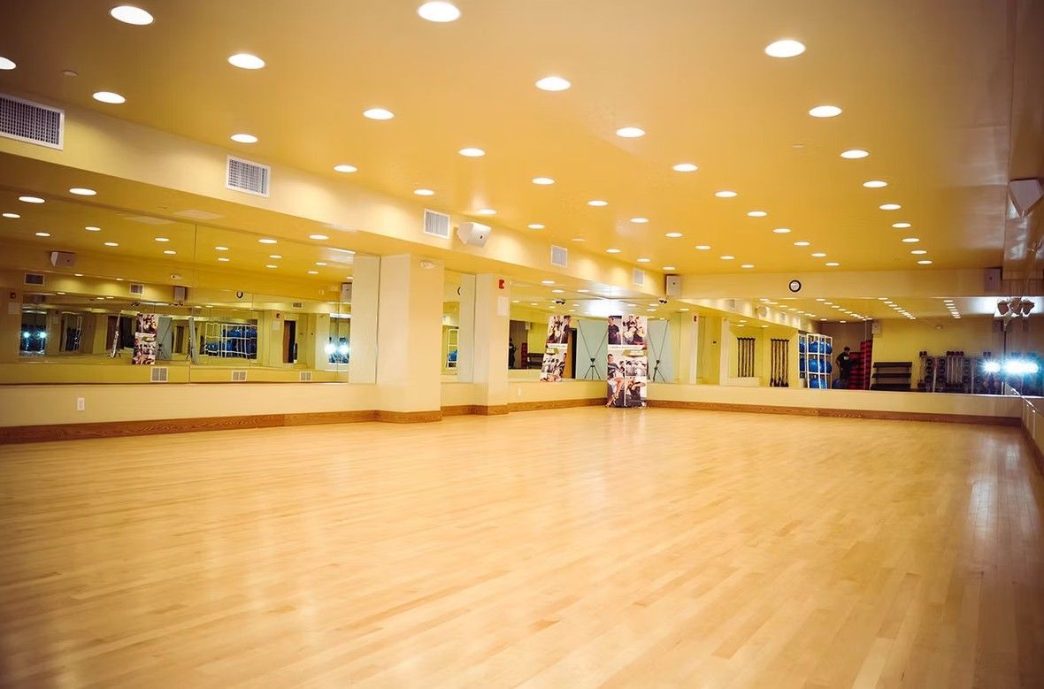 Empty mirrored dance studio with polished wooden floor and bright ceiling lights