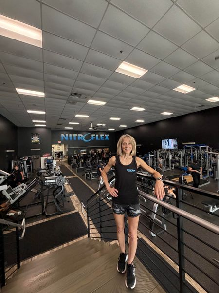 Person standing on a gym ramp by exercise equipment in a bright fitness center