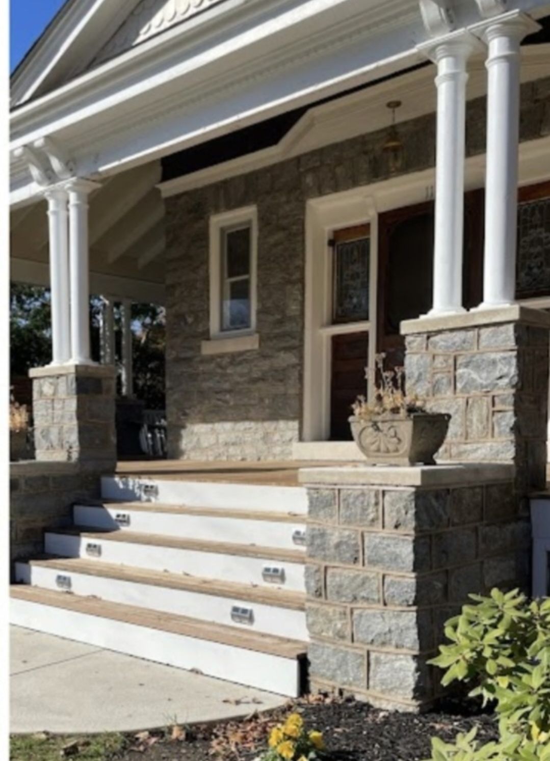 Stone facade and steps leading to a house with columns.