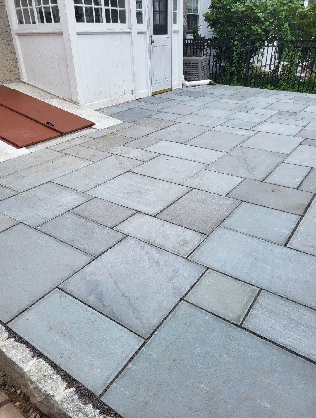 Blue stone patio with white building and door.