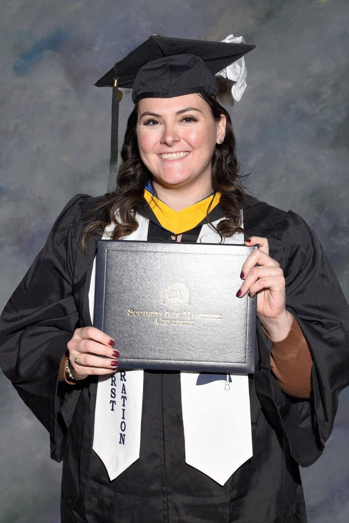 Woman in a graduation cap and gown holding her degree