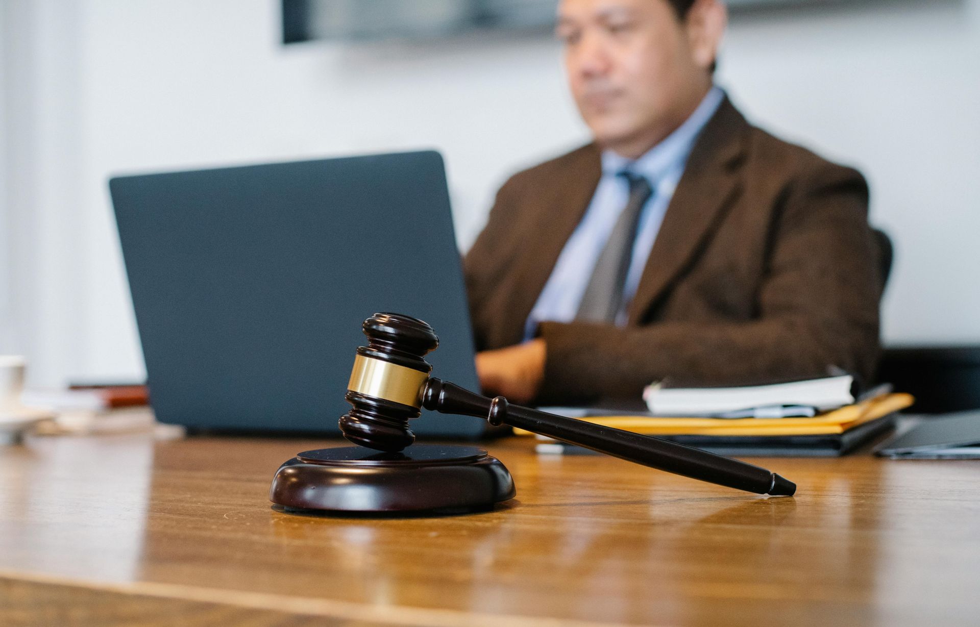 Judge’s gavel on a desk in front of a laptop, with a blurred lawyer in the background