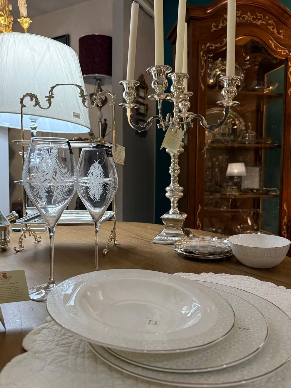 Una mise en place elegante con cristalleria luminosa, tovagliato neutro e dettagli floreali delicati.