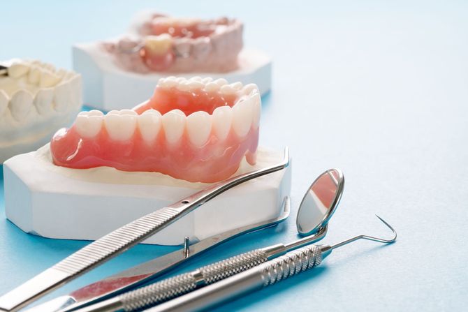 Protesi dentarie con strumenti odontoiatrici su una superficie azzurra