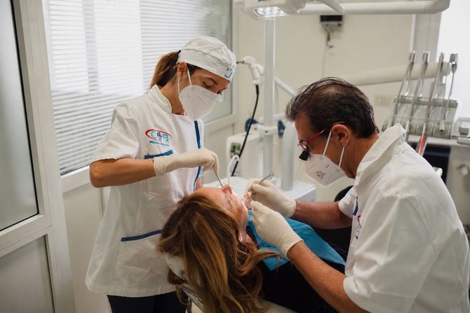 Un dentista regola l'apparecchio ortodontico di un paziente in una clinica odontoiatrica.