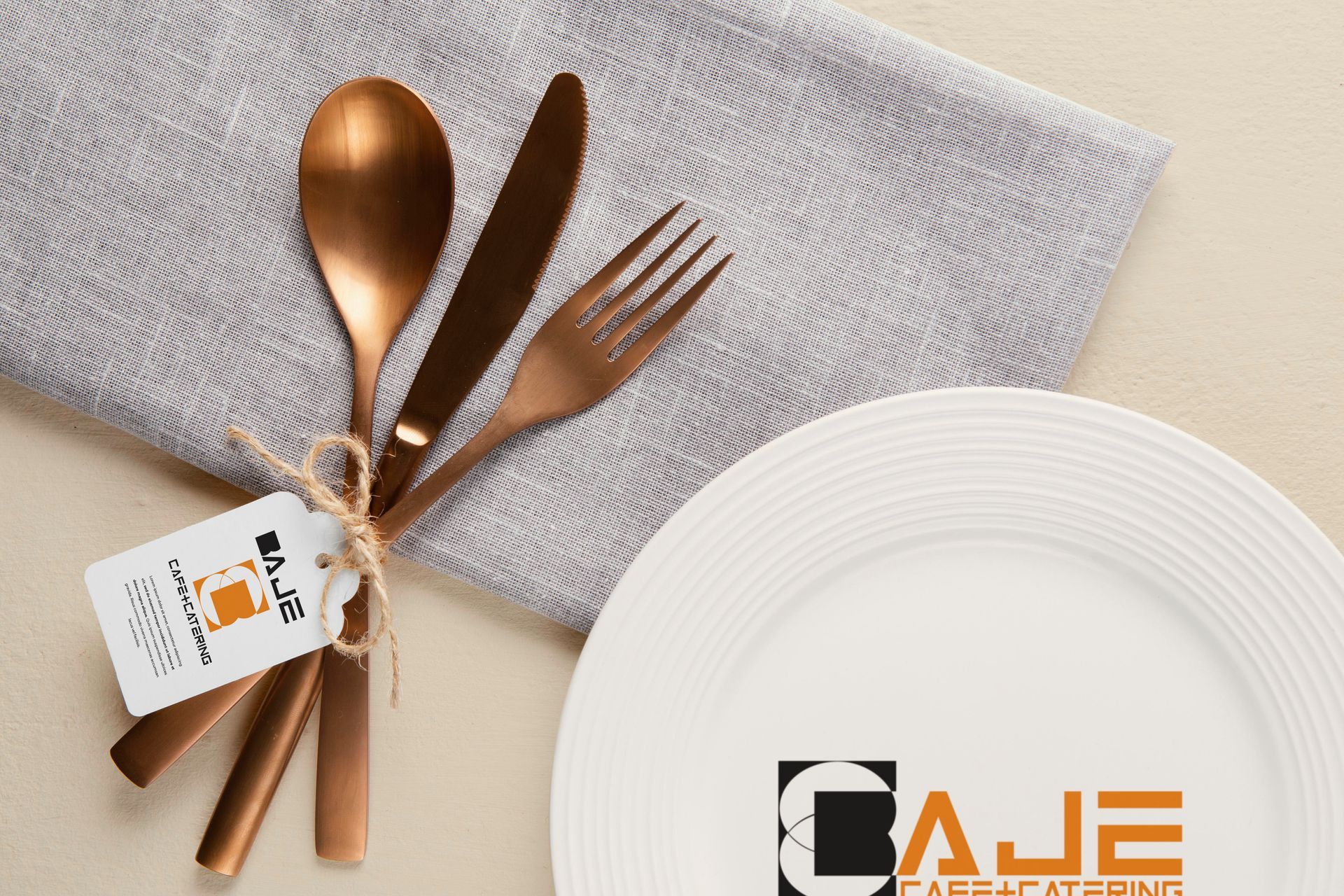 A white plate with copper utensils and a tag on it featuring baje cafe and catering logos