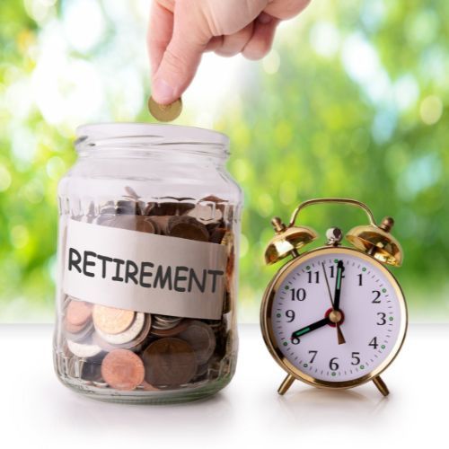A person is putting a coin into a retirement jar next to an alarm clock