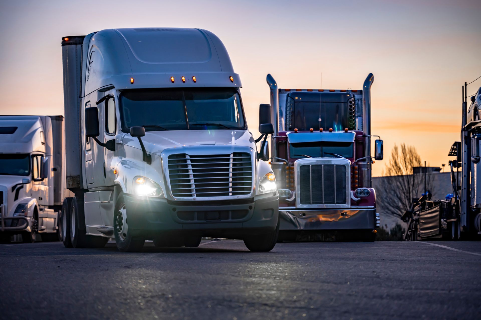 A row of semi trucks are parked on the side of the road.