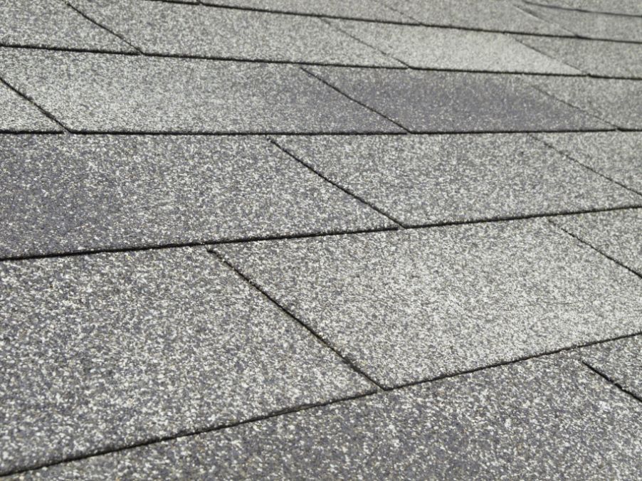 Close-up of gray asphalt roof shingles, arranged in overlapping rows.