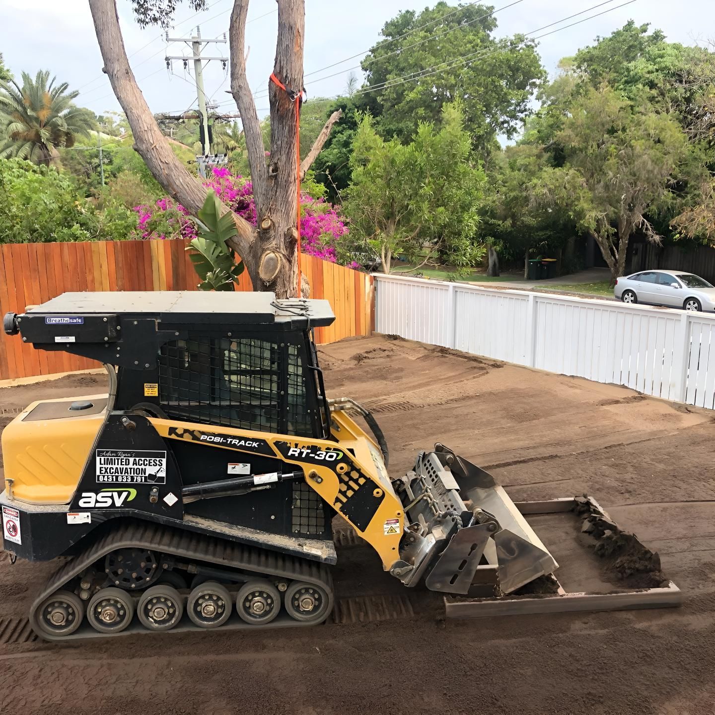 A Yellow and Black Bulldozer is Sitting in the Dirt in Front of a Fence — Limited Access Excavation In Alstonville, NSW
