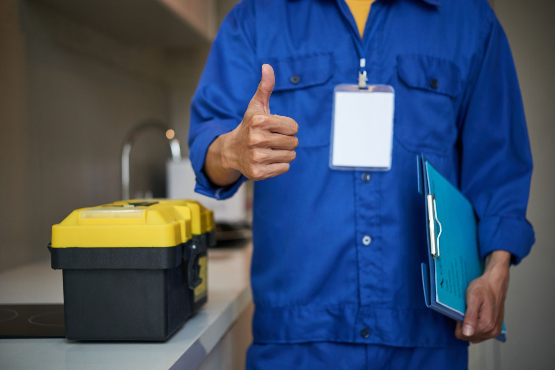 Un manitas con un mono azul hace un gesto de aprobación con el pulgar hacia arriba, sosteniendo un portapapeles junto a una caja de herramientas amarilla.