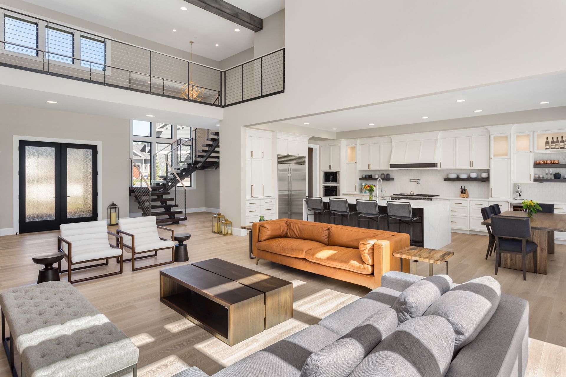 Bright open-concept living room with gray sofas, wood coffee table, and white kitchen with dining area