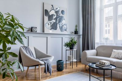 Modern living room with gray sofas, a plant, and abstract wall art by a bright window