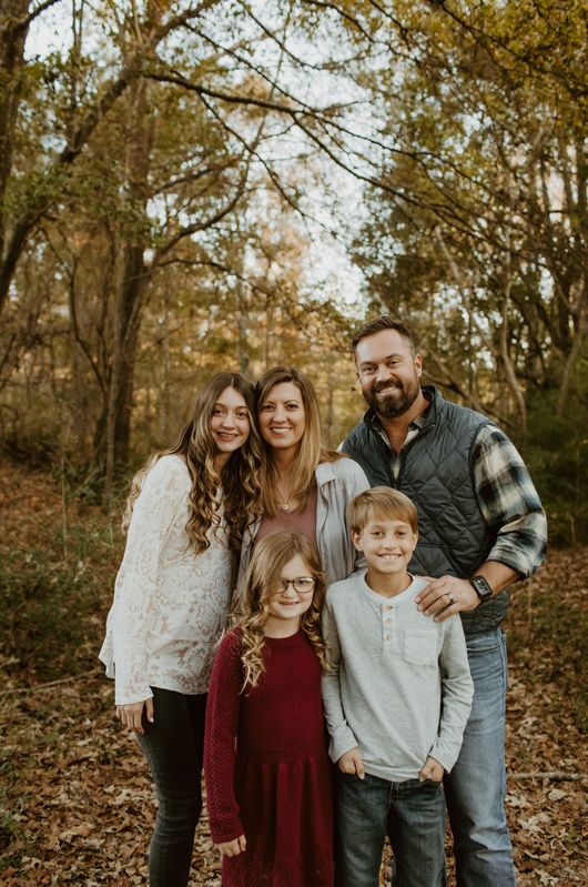 A family is posing for a picture in the woods.
