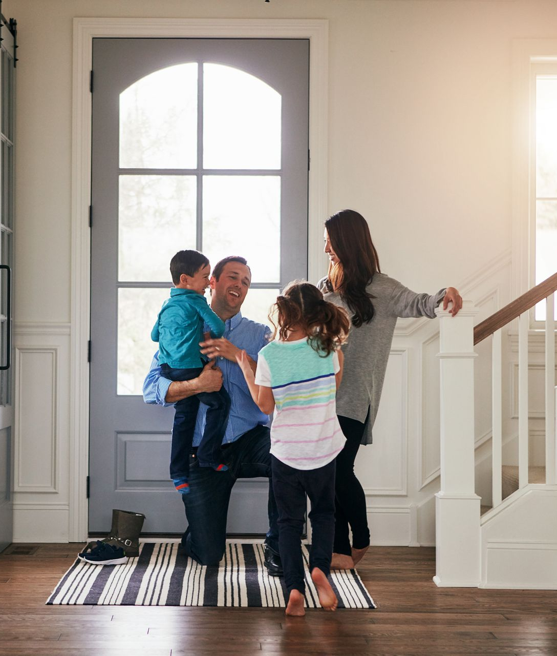 Family greeting each other in a bright entryway by the front door