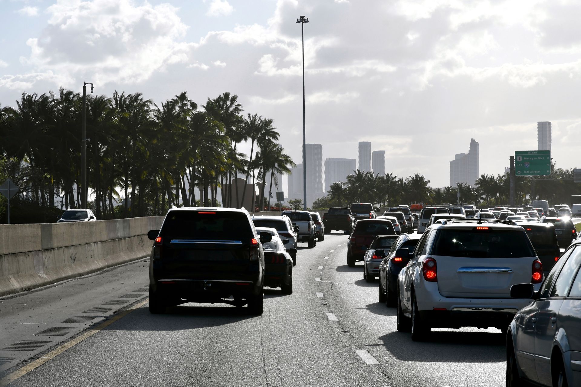 Traffic jam on a wet highway with several cars and a distant city skyline under cloudy skies