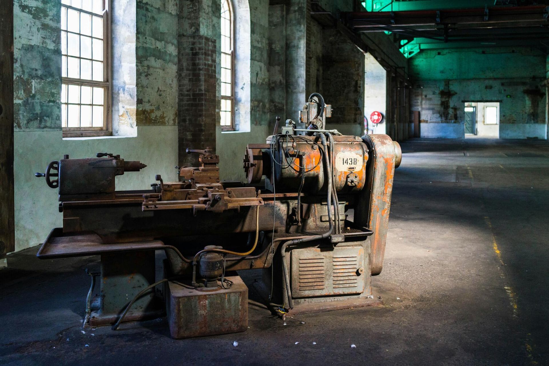 An old rusty machine is sitting in a dark room next to a window.