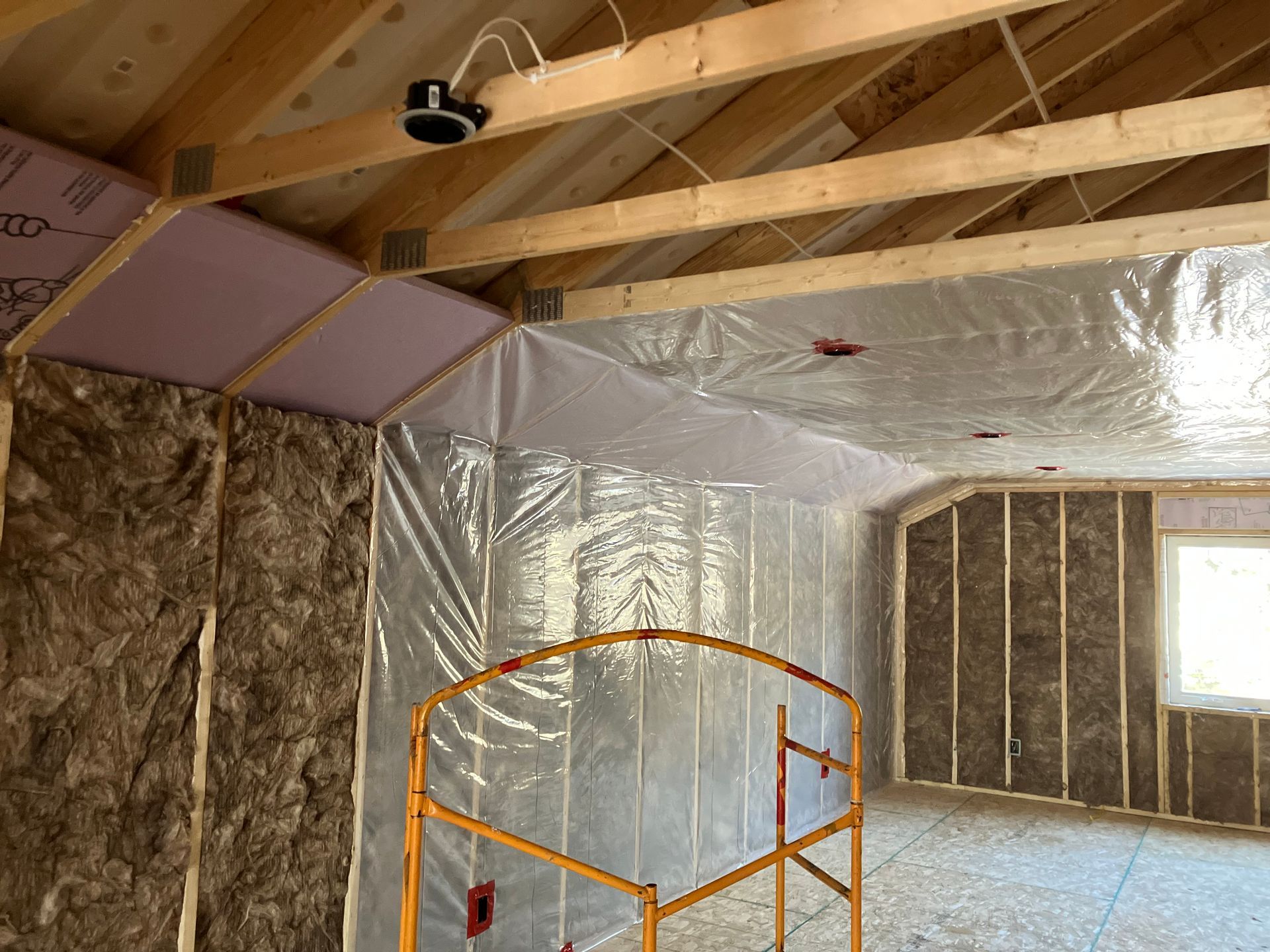 Interior of a room under construction, insulated with spray foam between wooden studs and rafters. Interior of a room under construction, insulated with spray foam between wooden studs and rafters.