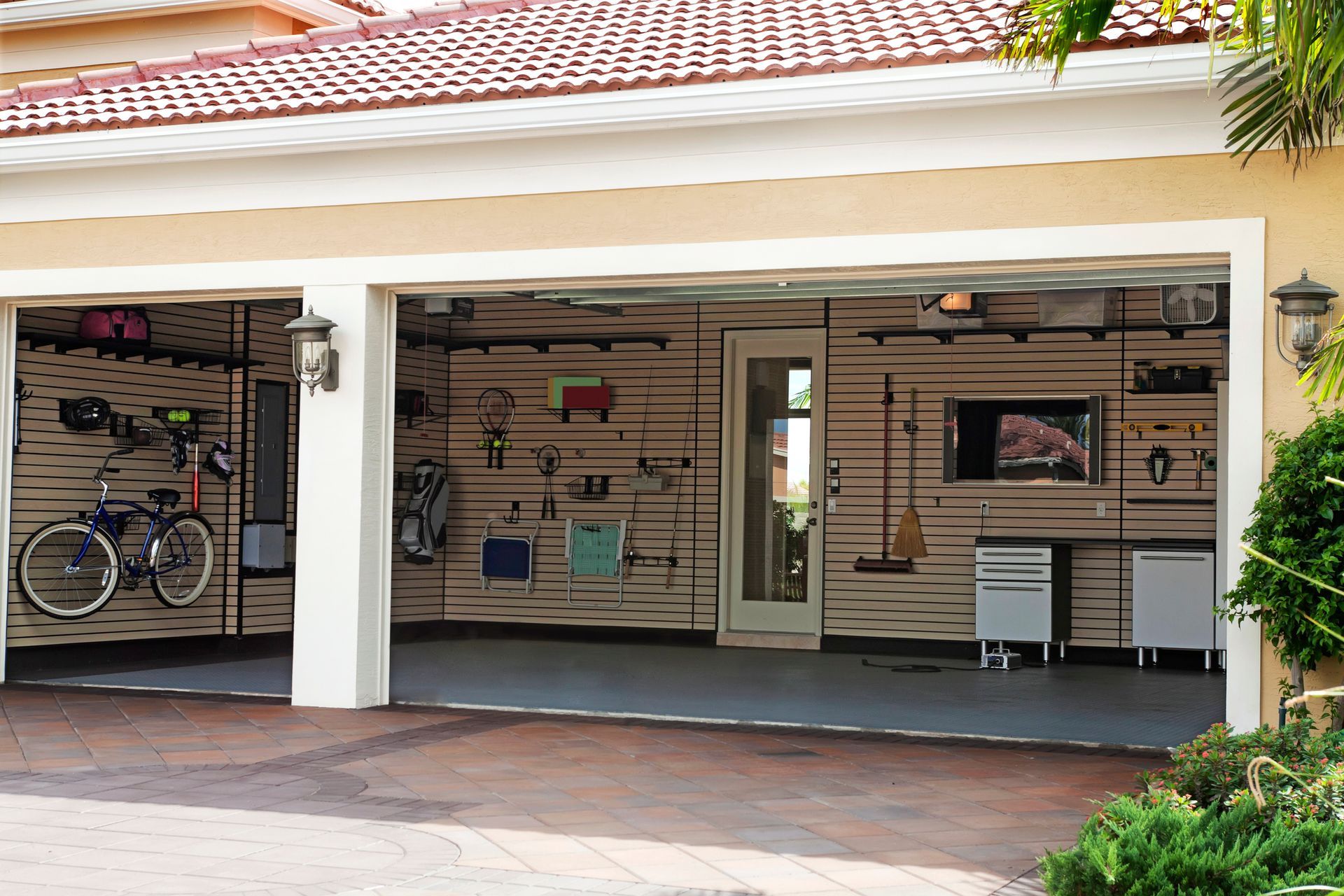 Two-car garage with open doors, organized storage, and a television. 