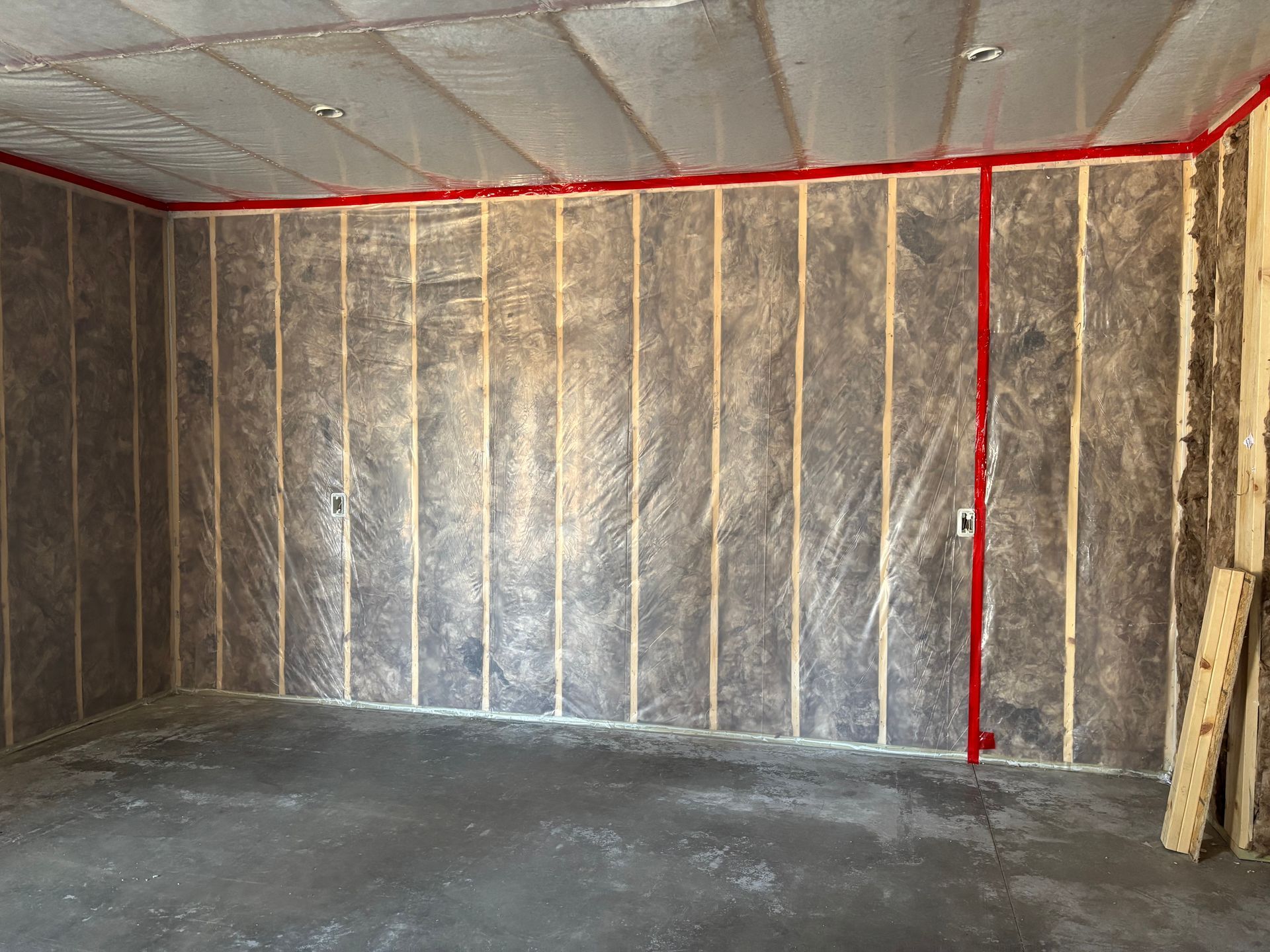 Insulation being installed in the walls and ceiling of a wooden frame house under construction. Insulation being installed in the walls and ceiling of a wooden frame house under construction.