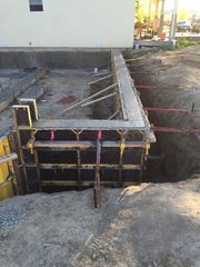 Concrete foundation formwork at a construction site beside an excavated trench
