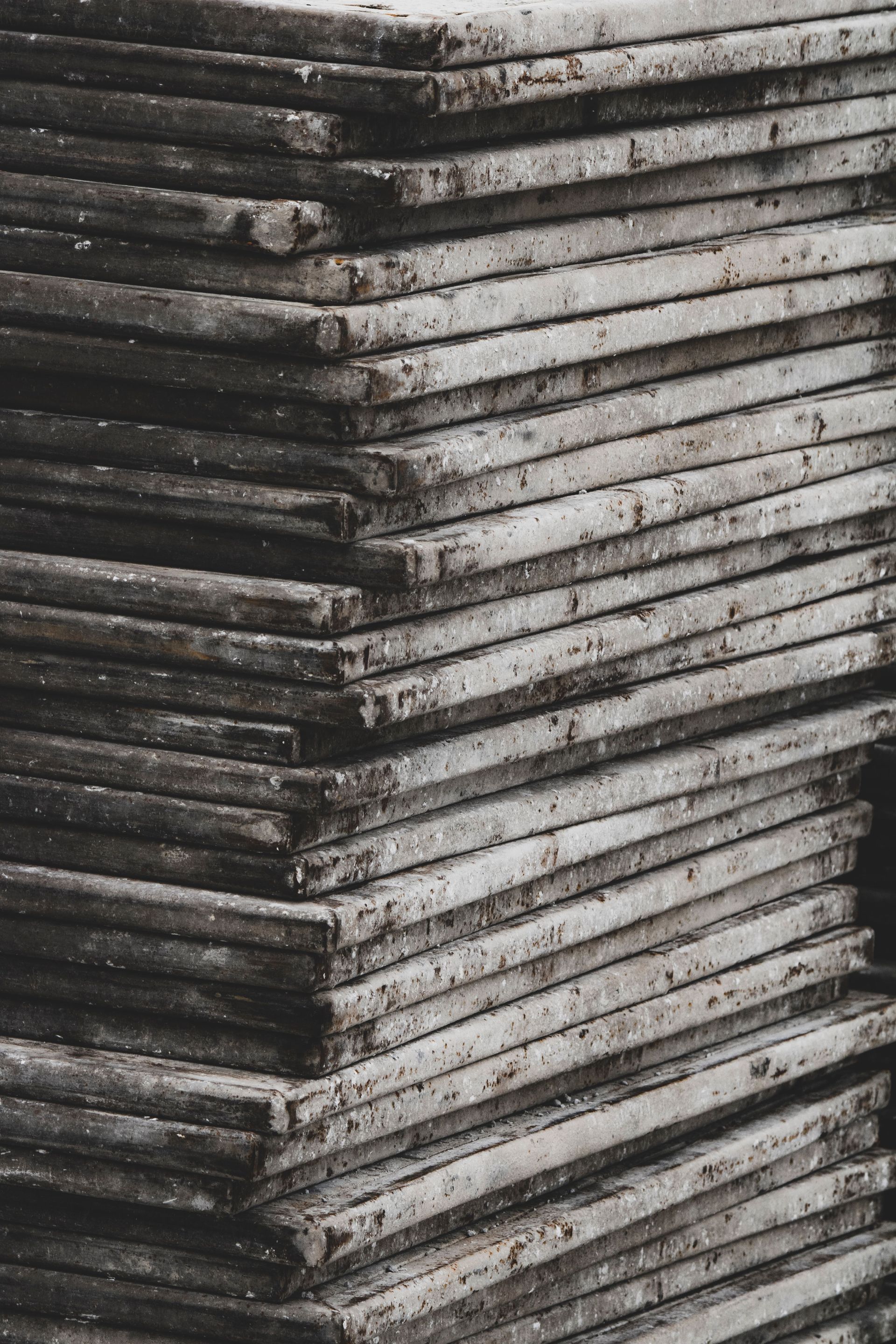 Stacked weathered metal sheets forming a rough, layered corner in black and gray tones