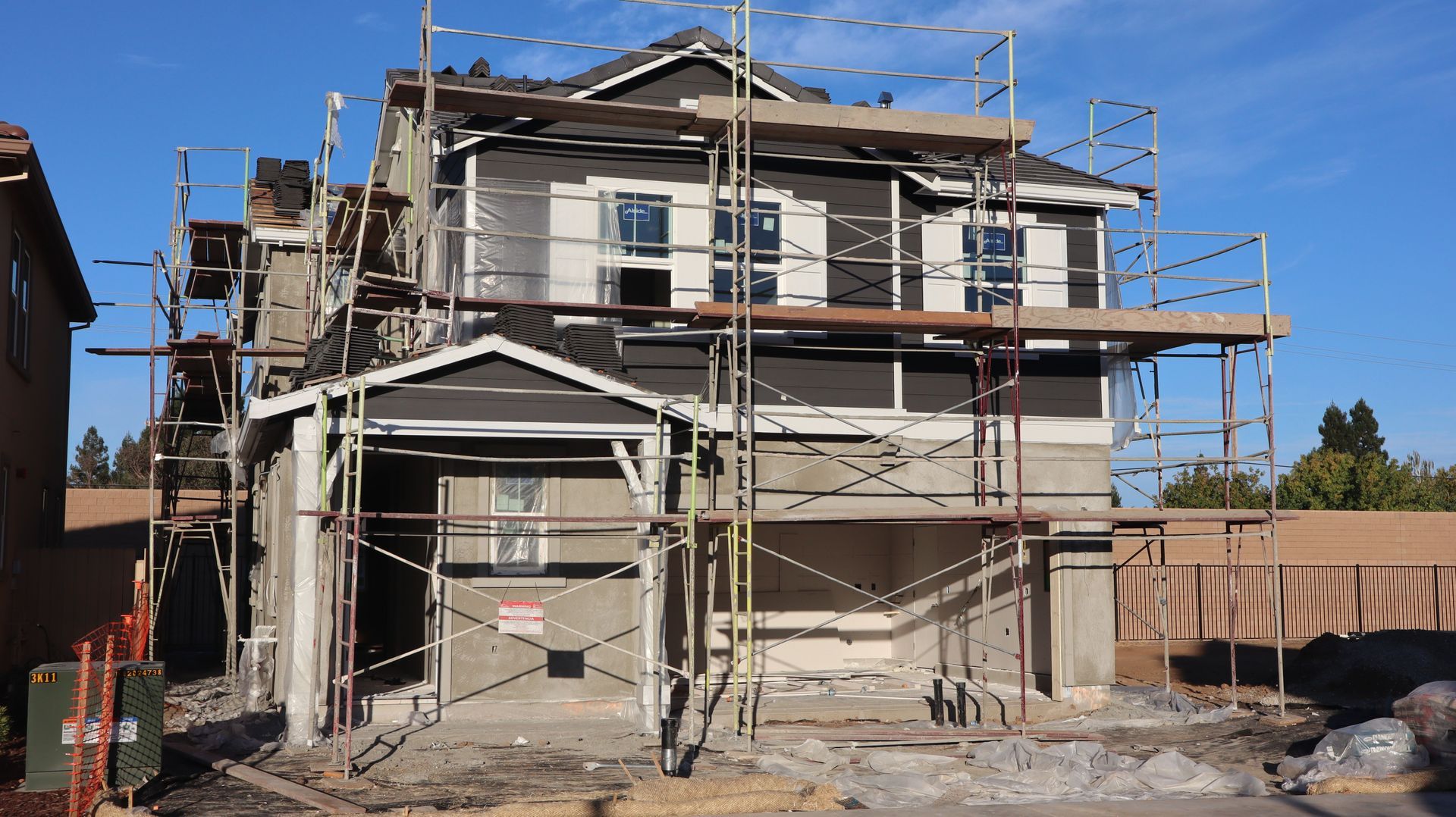 Two-story house under construction with scaffolding and blue sky