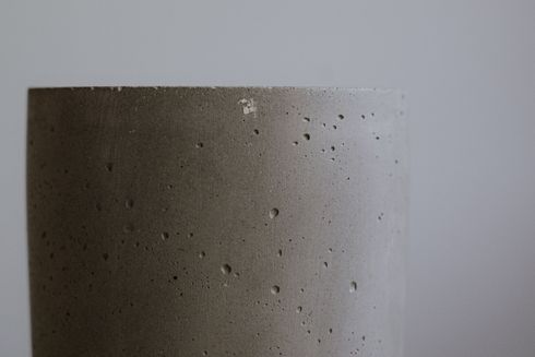 Close-up of a beige textured wall with small dark specks and soft lighting