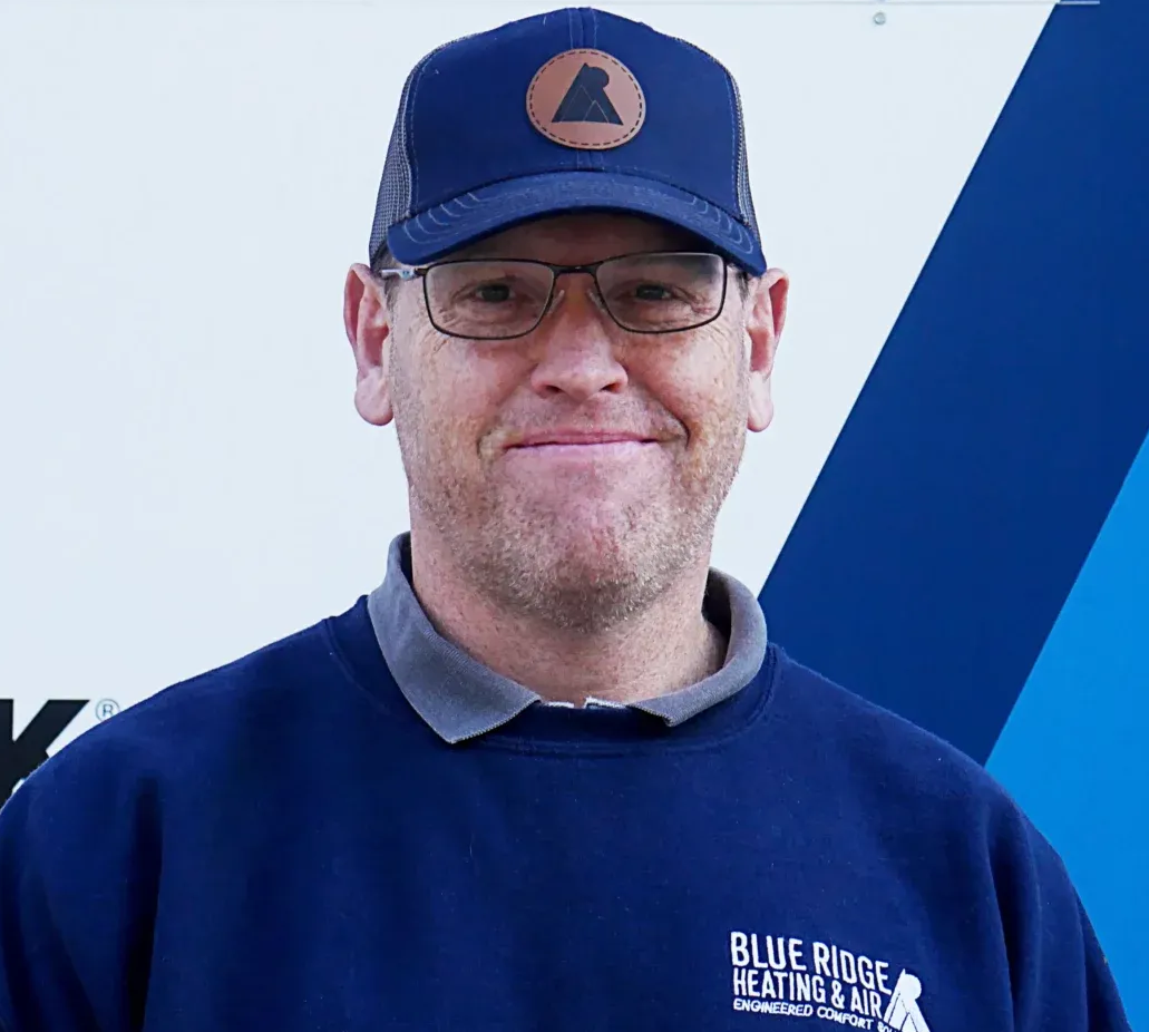 Man wearing glasses and hat, blue shirt with company logo.
