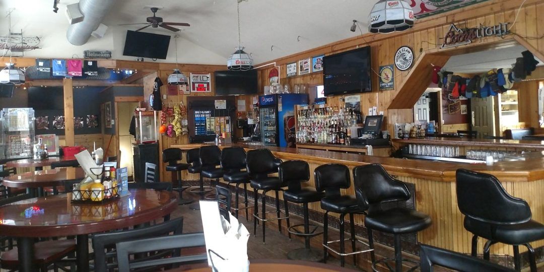 The inside of a restaurant with tables and chairs and a bar.