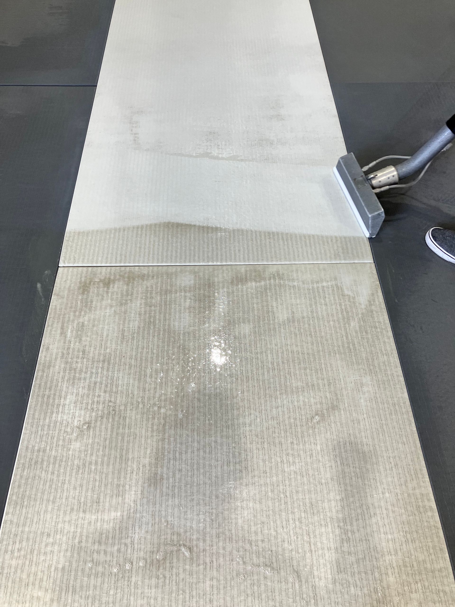 Close-up of a light beige rug being vacuumed on a dark floor.