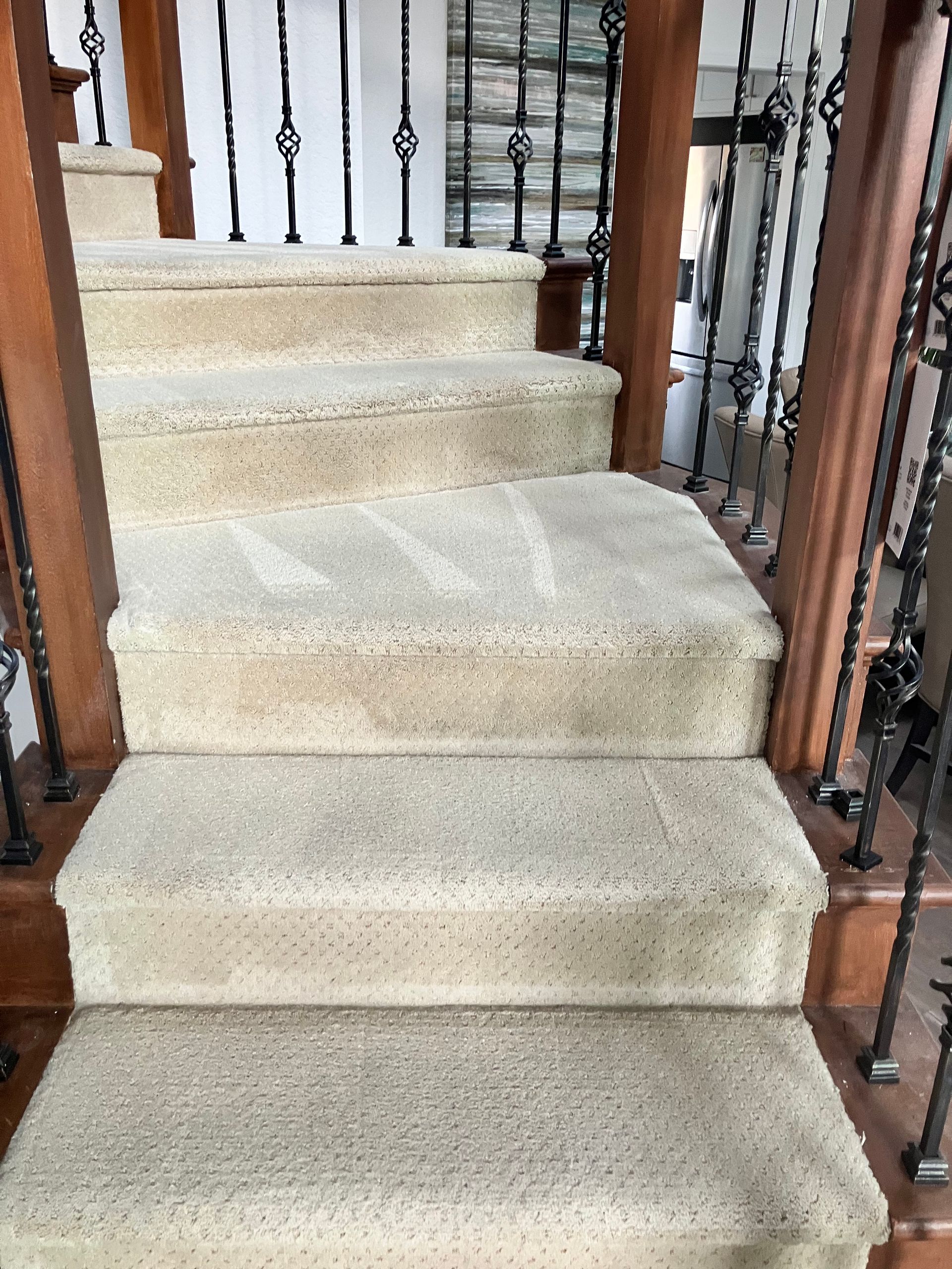 Carpeted staircase with wooden banisters and black metal railings in a home interior