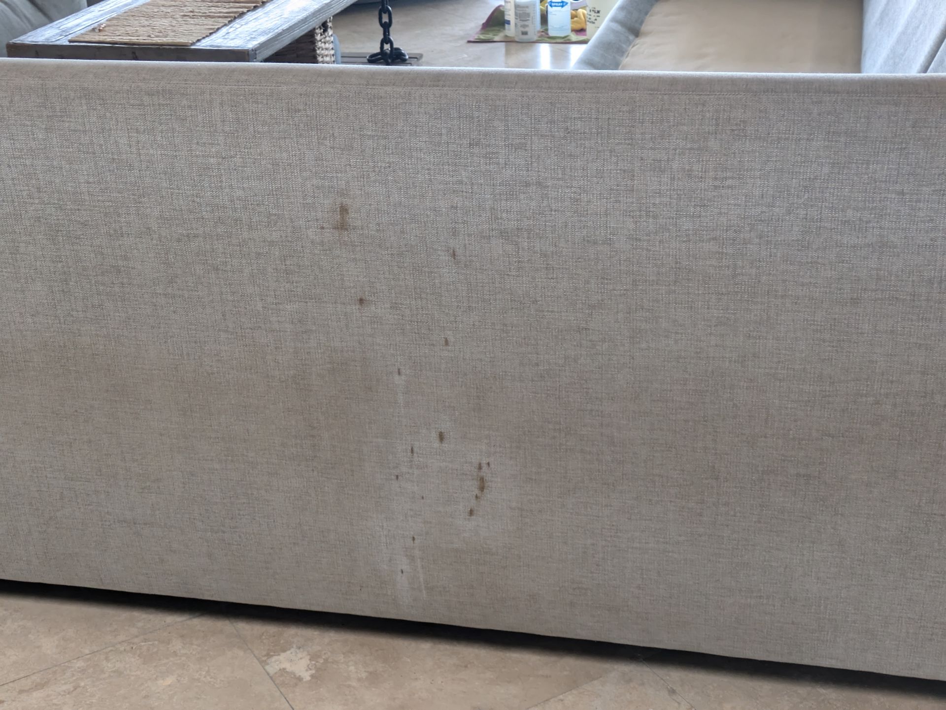 Beige upholstered sofa back with visible stains and wear
