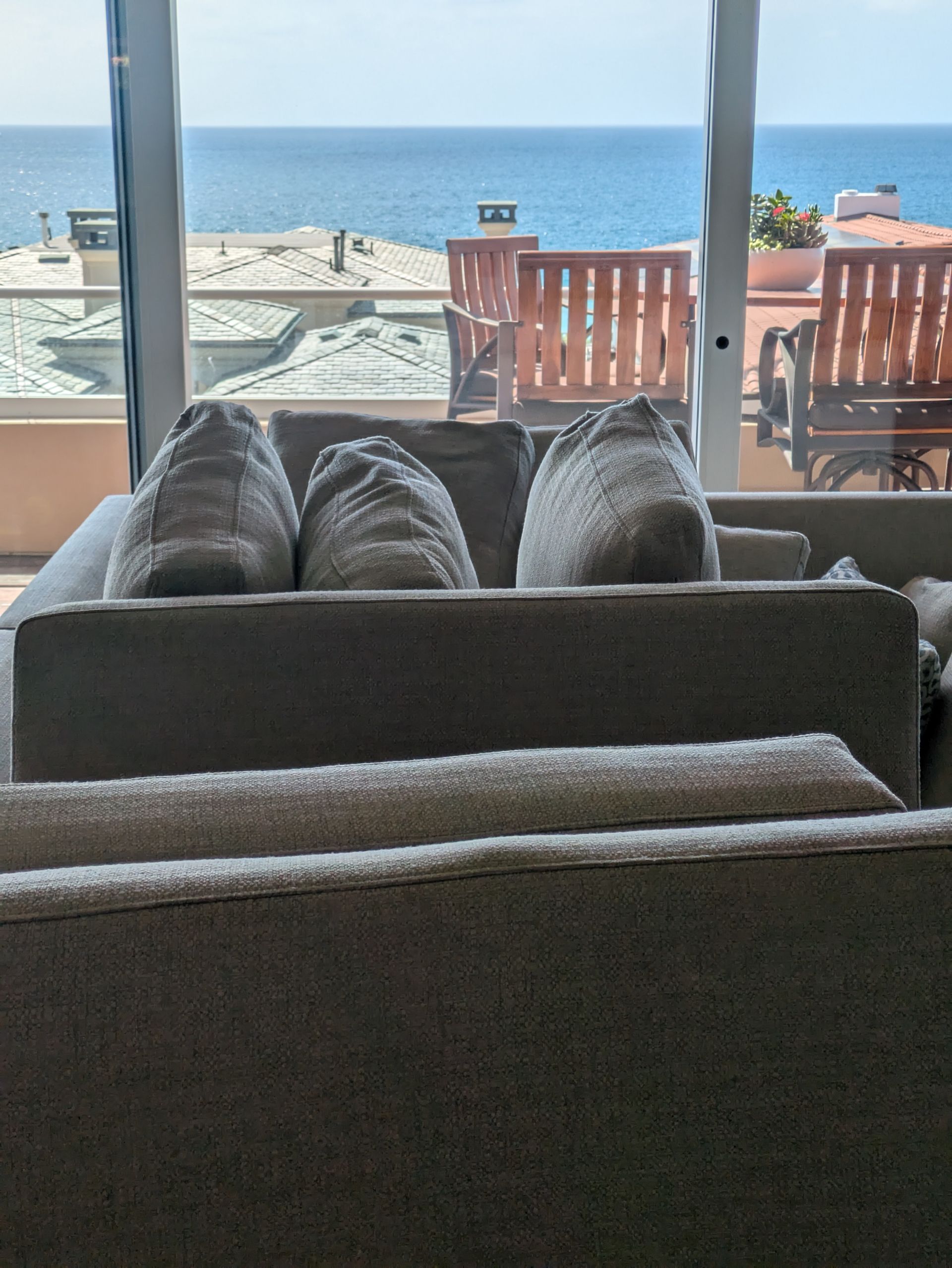 Living room sofas facing a bright ocean view through large windows