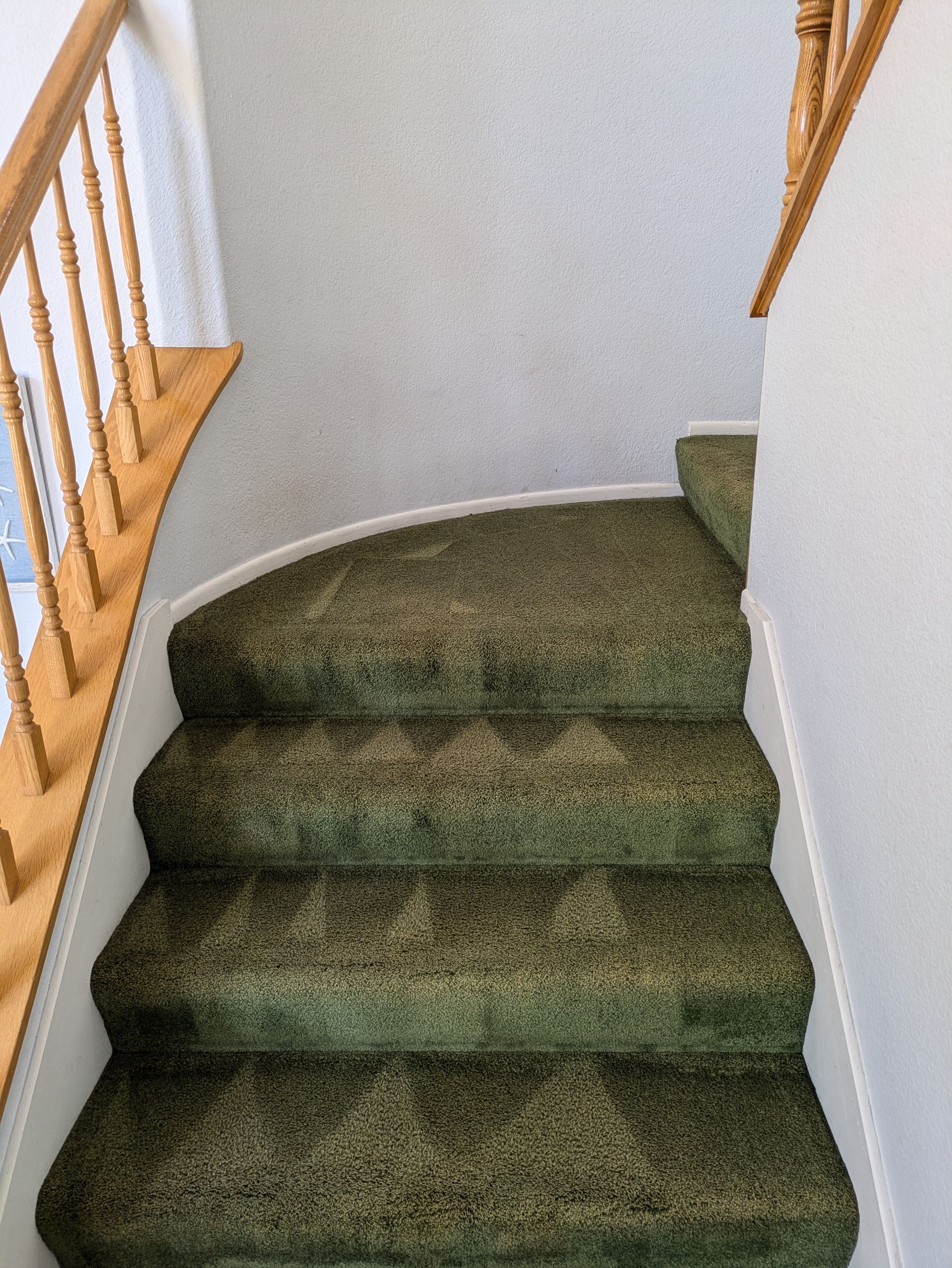 Carpeted staircase landing with white walls and light wood railing.