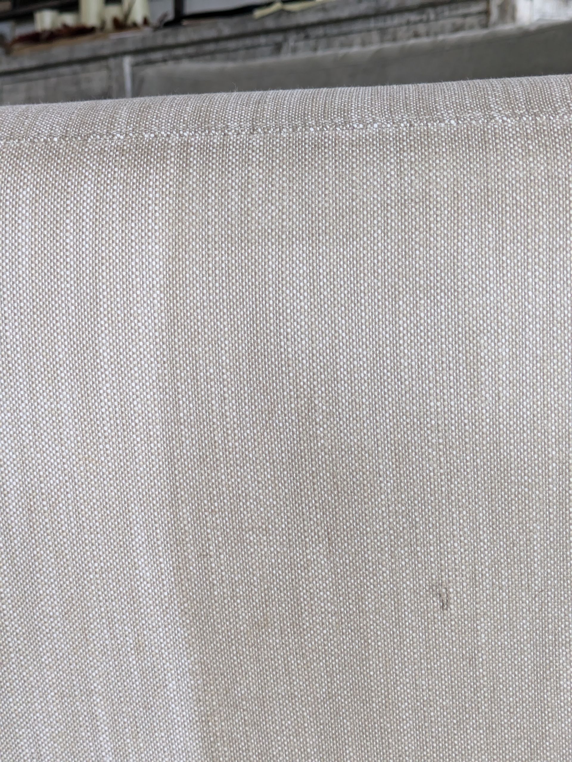 Close-up of light beige textured fabric with a seam at the top edge