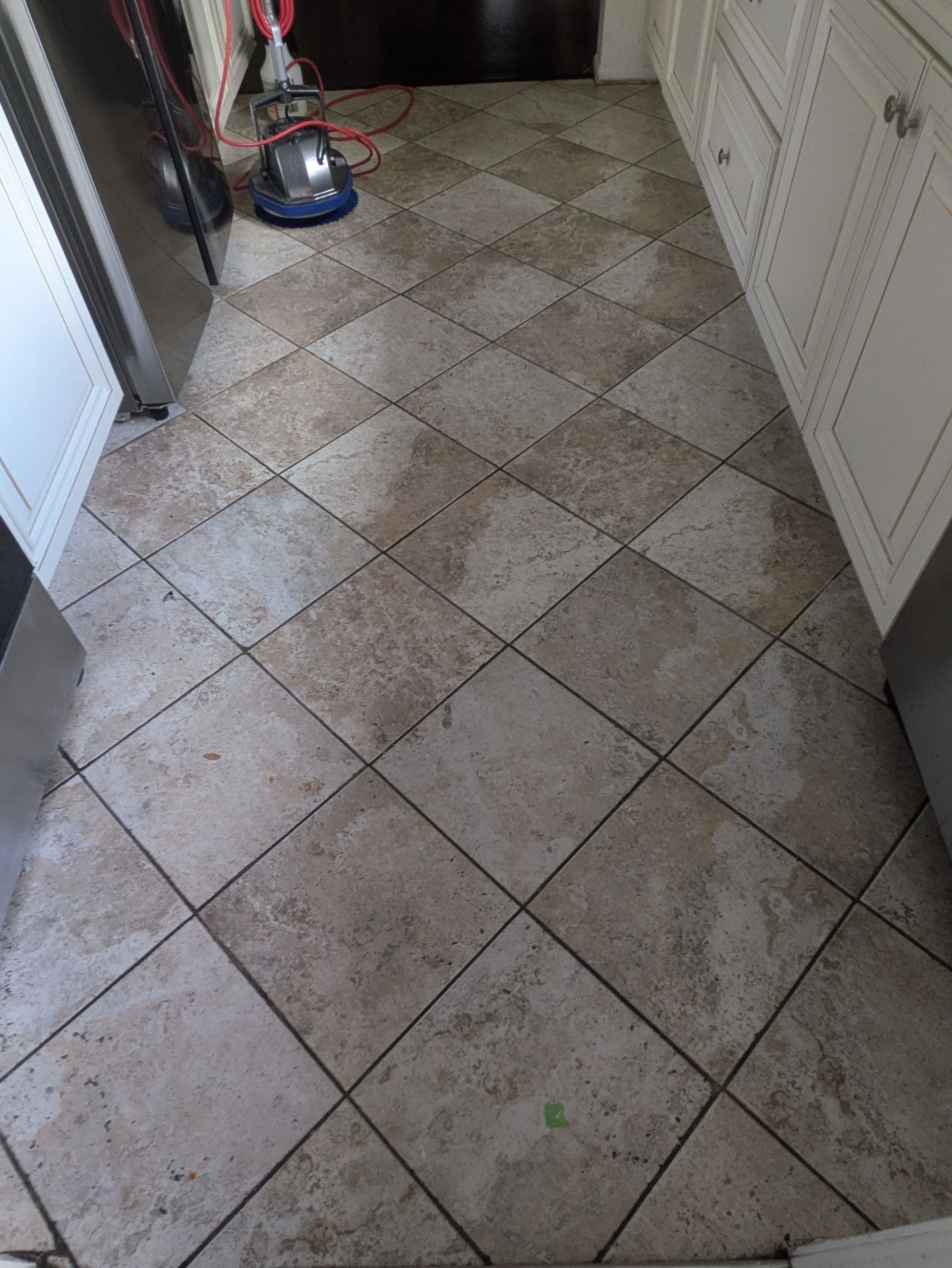 Tiled hallway floor with a red and blue bag near the wall and a white door on the right