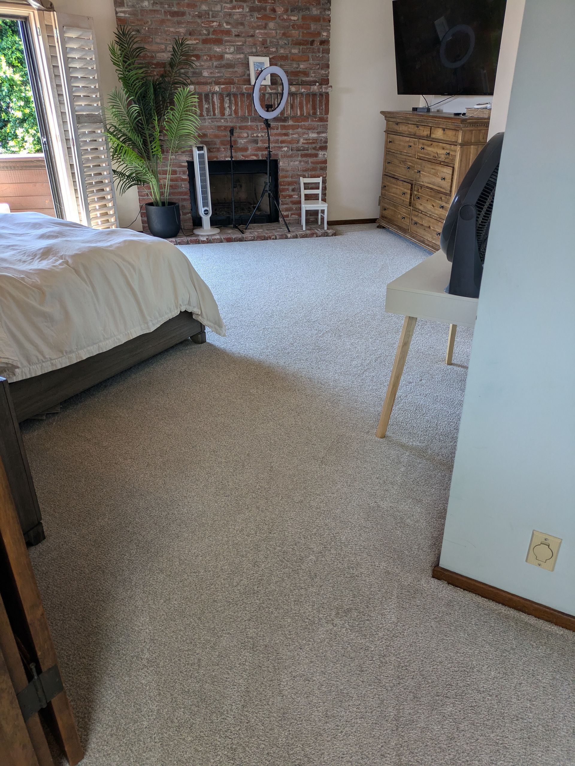 Bedroom with bed, carpet, exposed brick wall, fireplace, and open doorway.