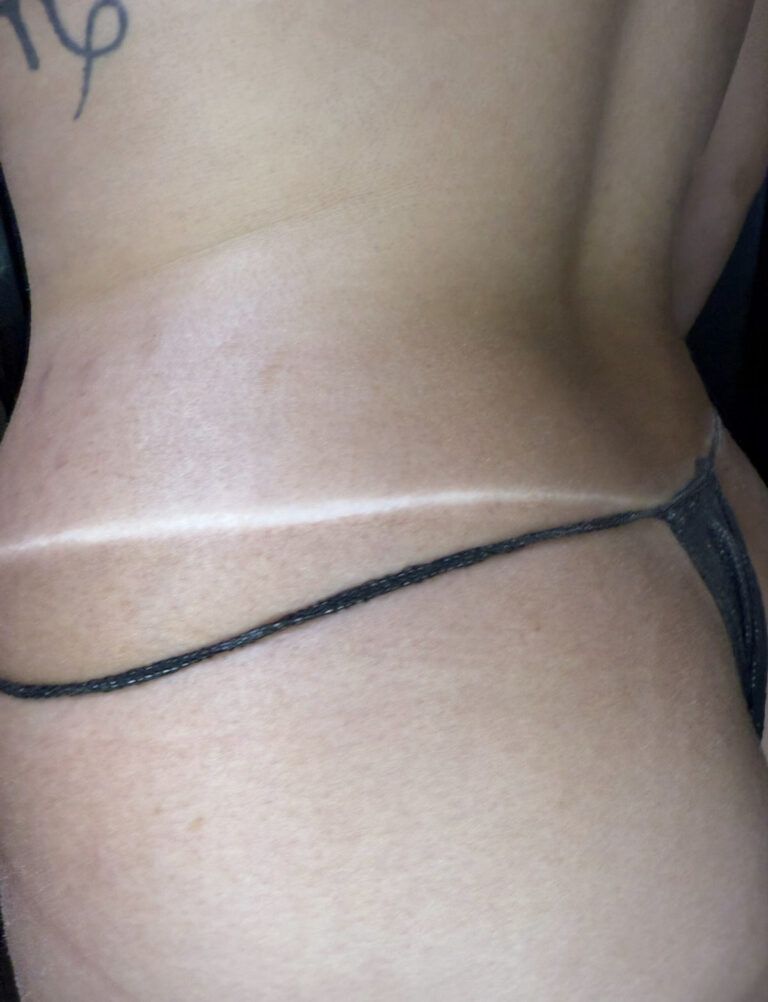 Back view of a bare lower back with a black string bikini bottom and a pale tan line.